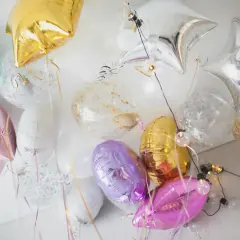 Kolorowe balony do helu w kształcie gwiazdek i okrągłe z konfetti, tworzą radosną dekorację.