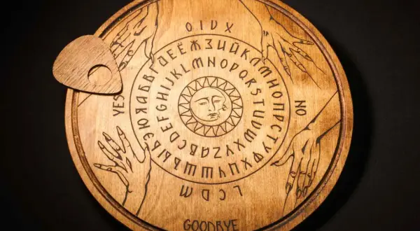 Drewniana plansza Ouija z literami, cyframi i symbolem słońca. Czy to sposób, jak wywołać ducha bez świeczek?