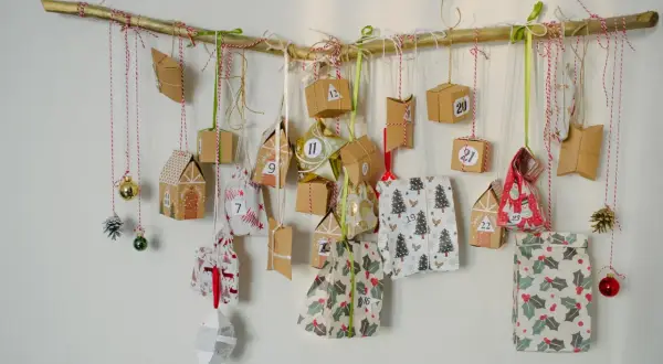 Ręcznie robiony kalendarz adwentowy dla mężczyzn diy wisi na gałęzi. Małe paczuszki i ozdoby świąteczne z numerami.