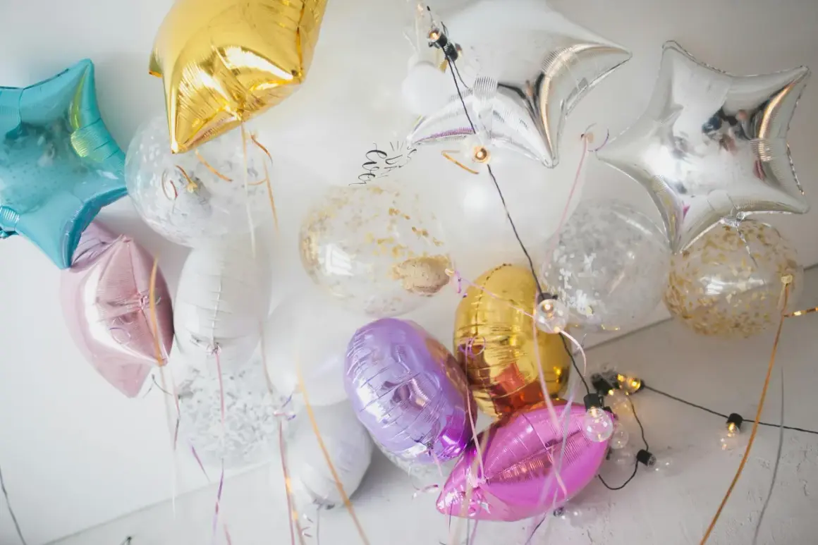 Kolorowe balony do helu w kształcie gwiazdek i okrągłe z konfetti, tworzą radosną dekorację.